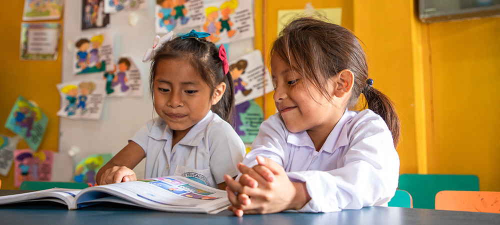 Twee meisjes uit Ecuador lezen een boek op school. 