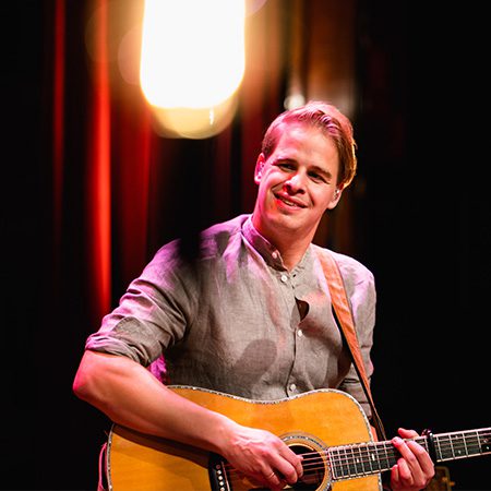 Foto van de Nederlandse liedjesschrijver en zanger Matthijn Buwalda die gitaar speelt.