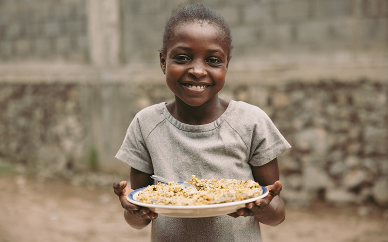 Rose Mirline uit Haïti heeft een bord met eten in haar hand.