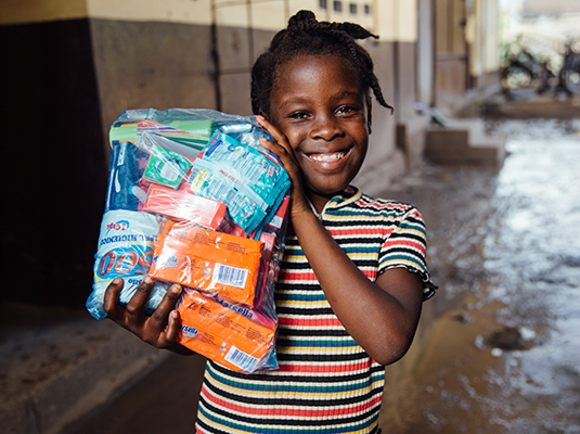 Meisje in Haiti met een voedselpakket in haar handen