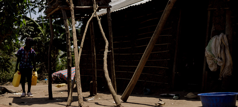 Acaali uit Uganda draagt twee jerrycans met water.