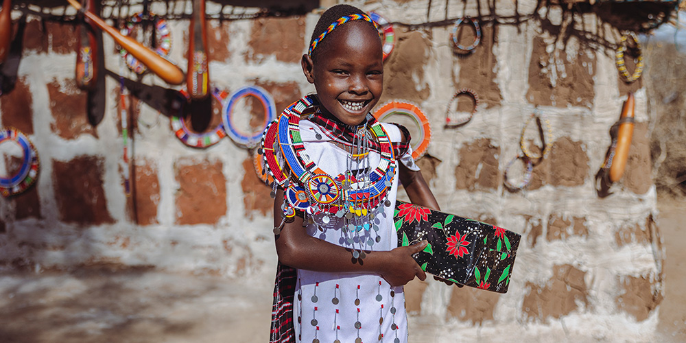 Pesi uit Kenia staat voor haar huis met een kerstcadeau in haar hand.