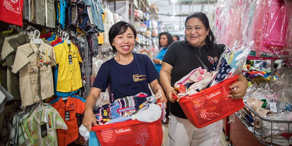 Projectmedewerkers Injilia en Donna uit Indonesië met twee winkelmandjes vol kerstcadeaus. 